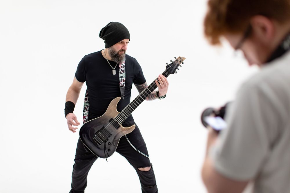 Musician in black clothing performs energetically with an electric guitar on stage.