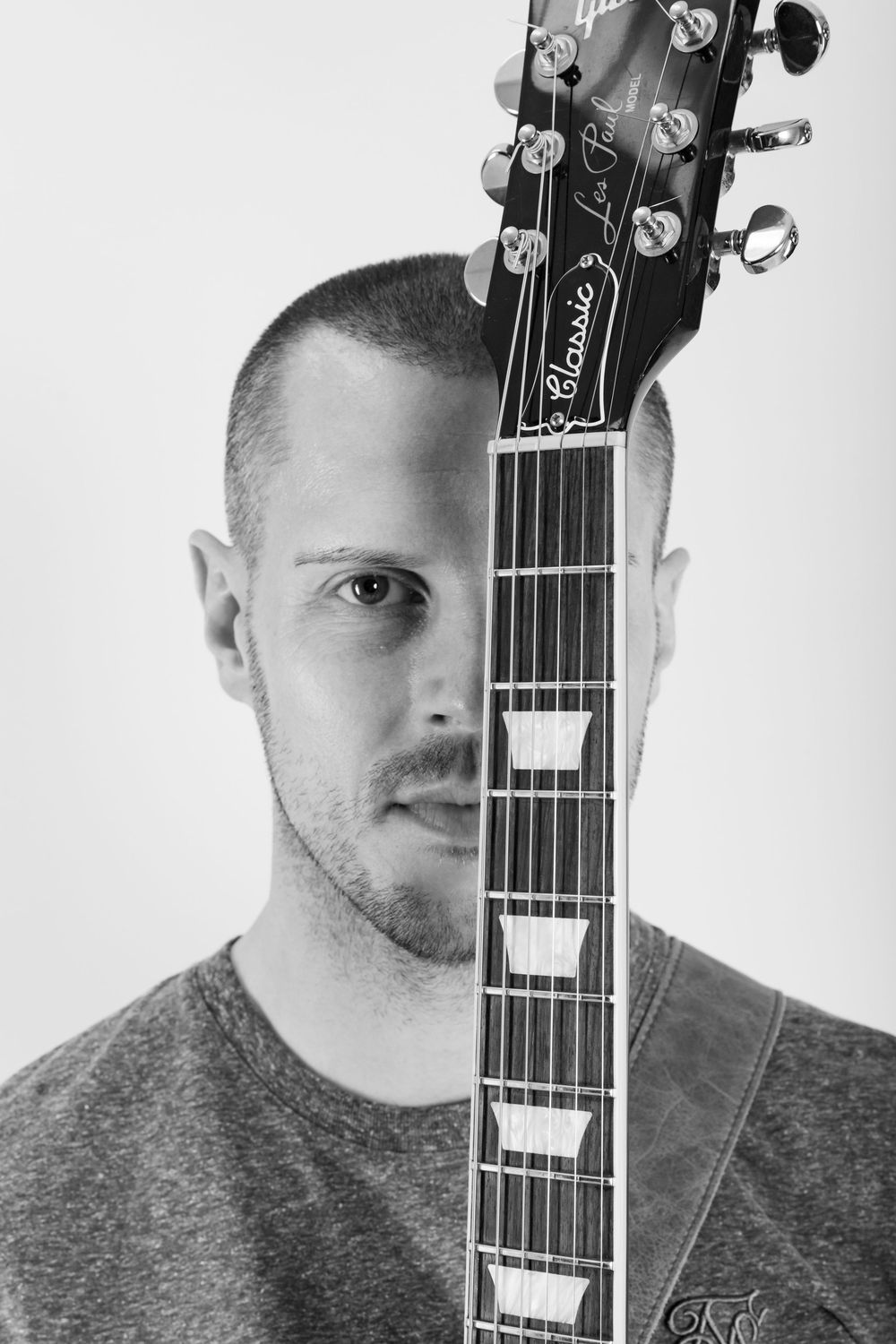 Creative portrait combining musician's face with neck of acoustic guitar in black and white.