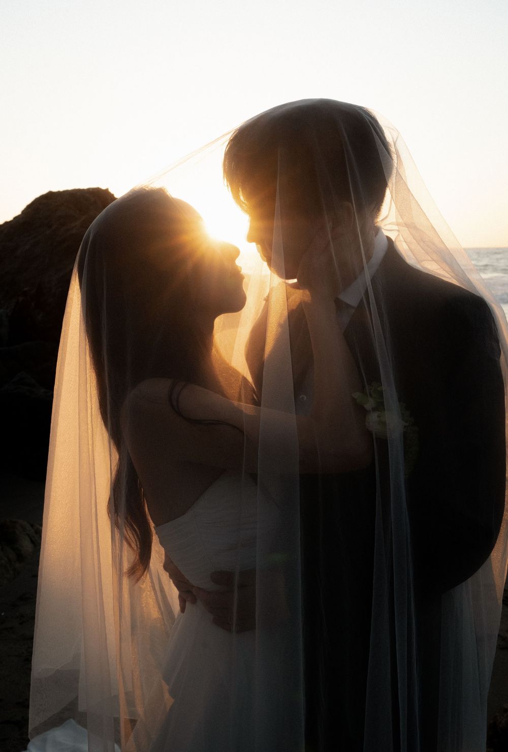 Silhouetted couple sharing romantic sunset kisses through a delicate veil in a series of intimate wedding portraits.
