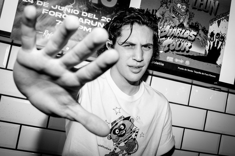 Black and white photo of young man reaching toward camera at an indoor music venue.