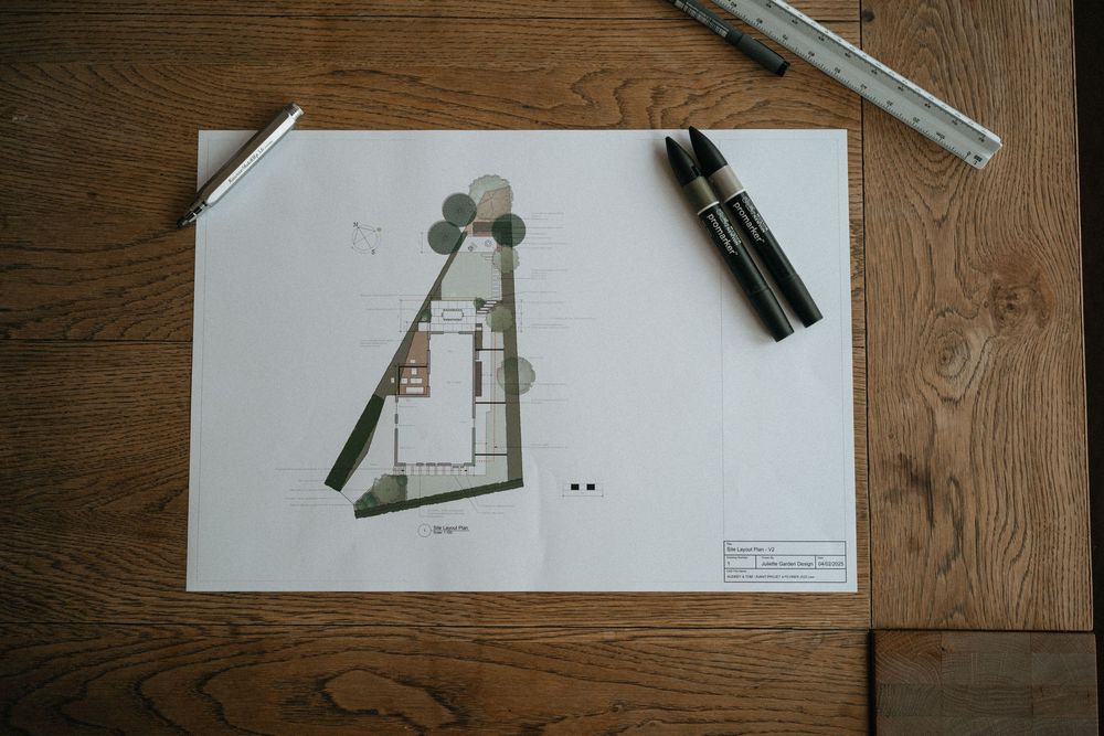 Technical drawings and sketches of mechanical parts laid out on a wooden surface with drafting tools.