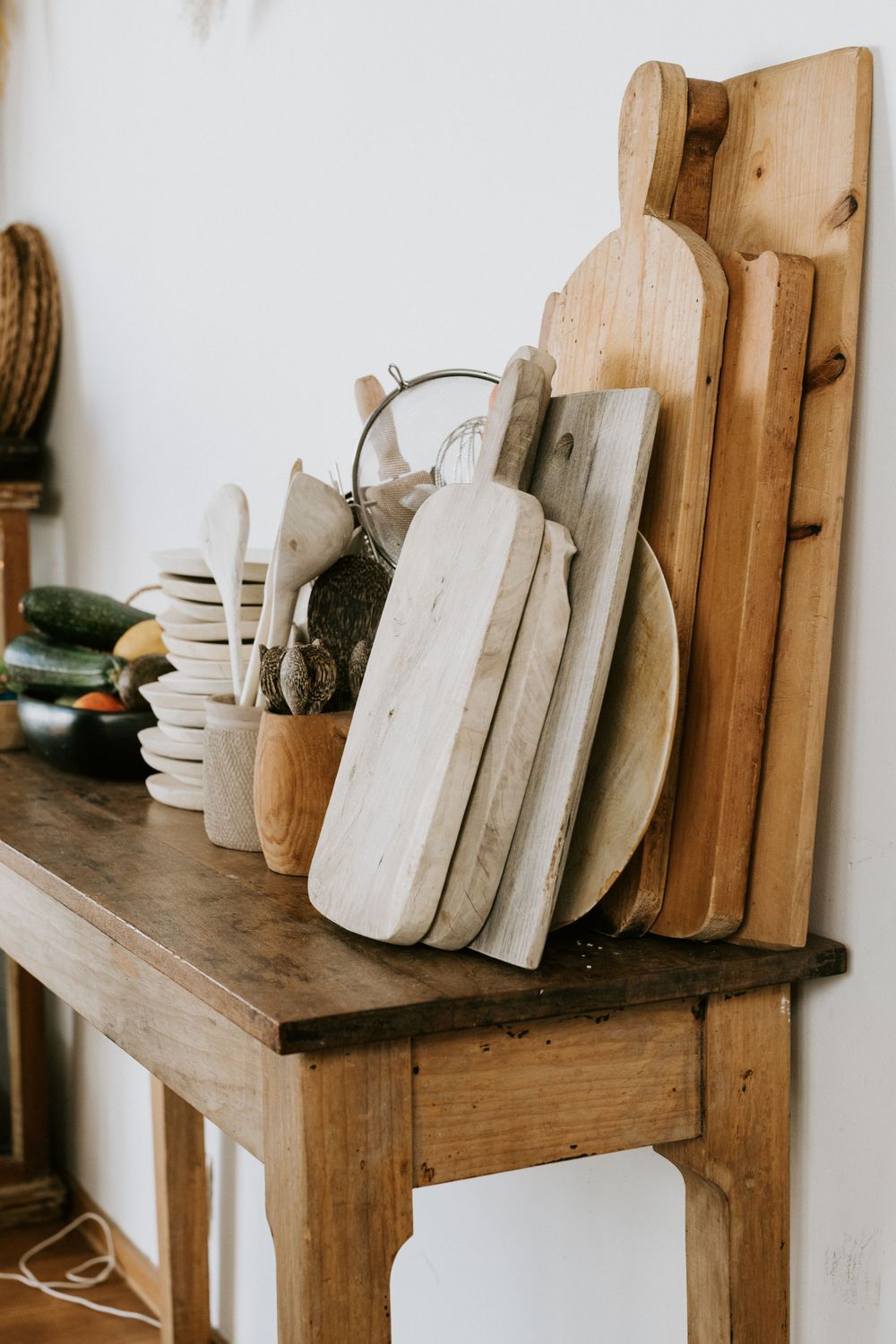 Collection of wooden cutting boards and kitchen utensils displayed on a rustic wooden table.