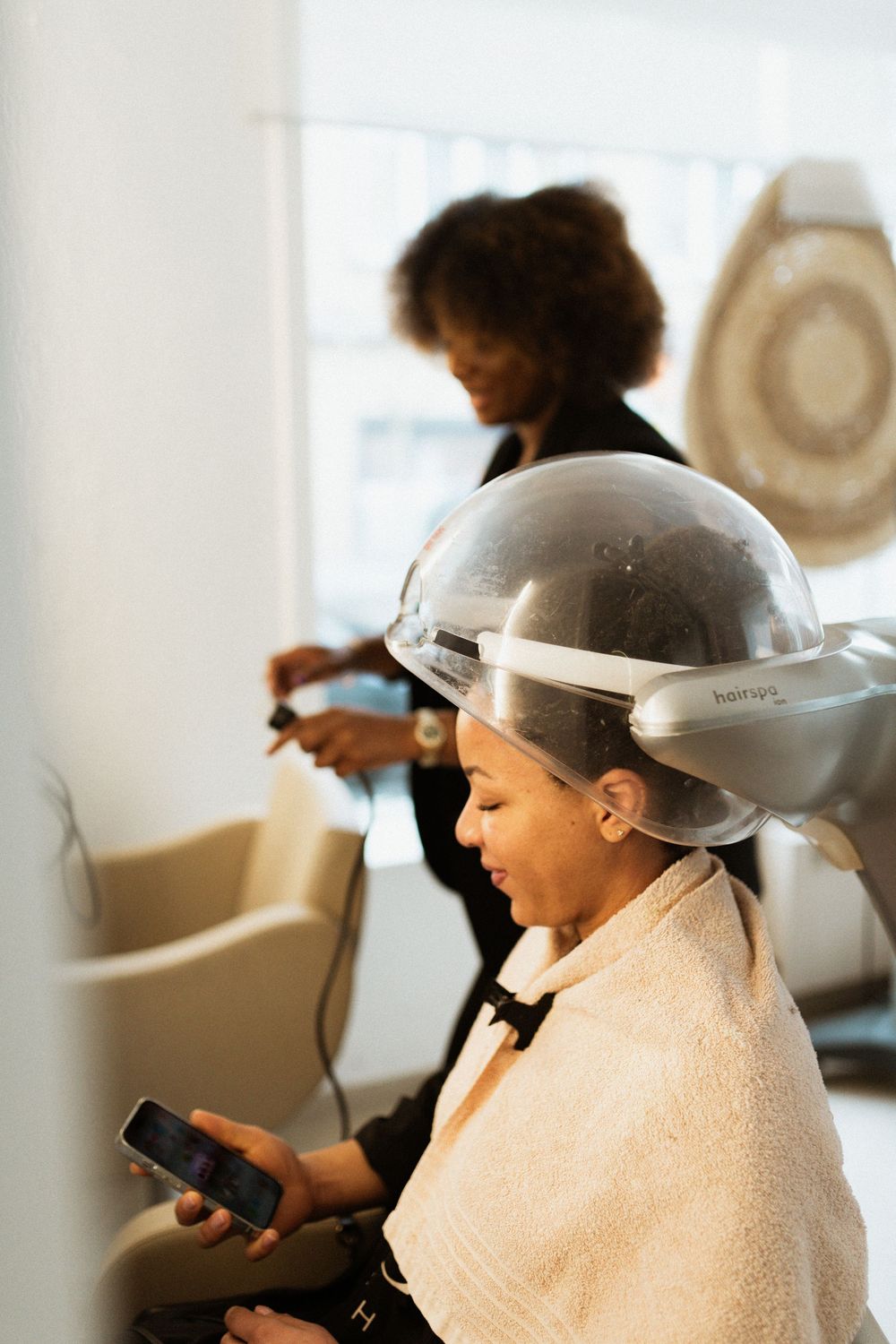 Beauty salon scene with professional hair dryer equipment in bright interior setting.