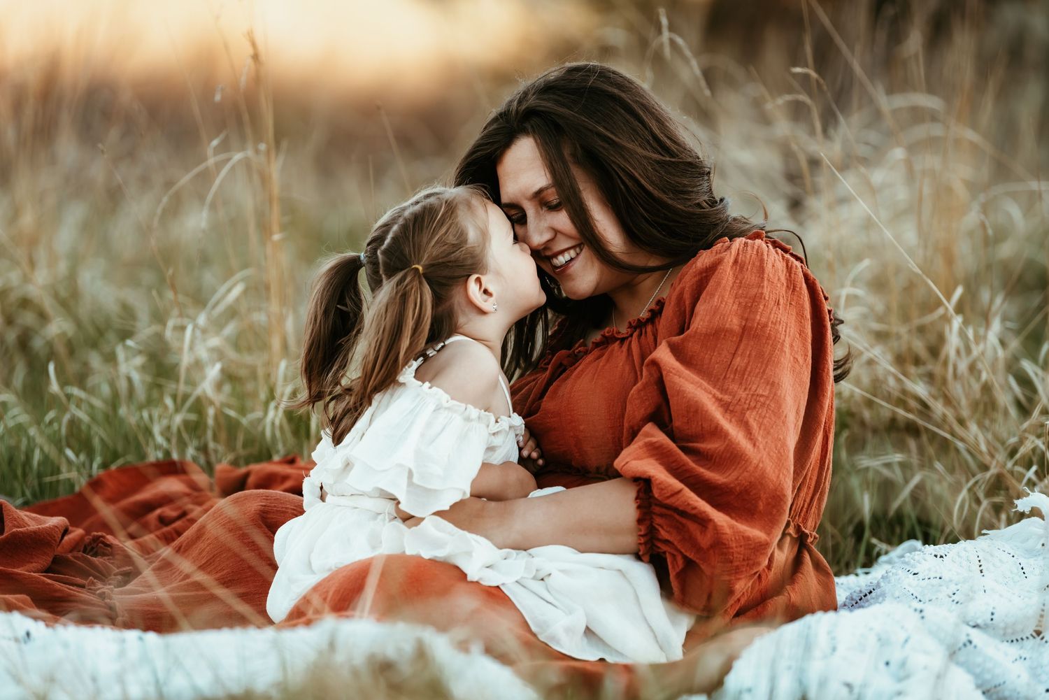 Intimate outdoor portrait in a field with warm sunset lighting and tall grass.