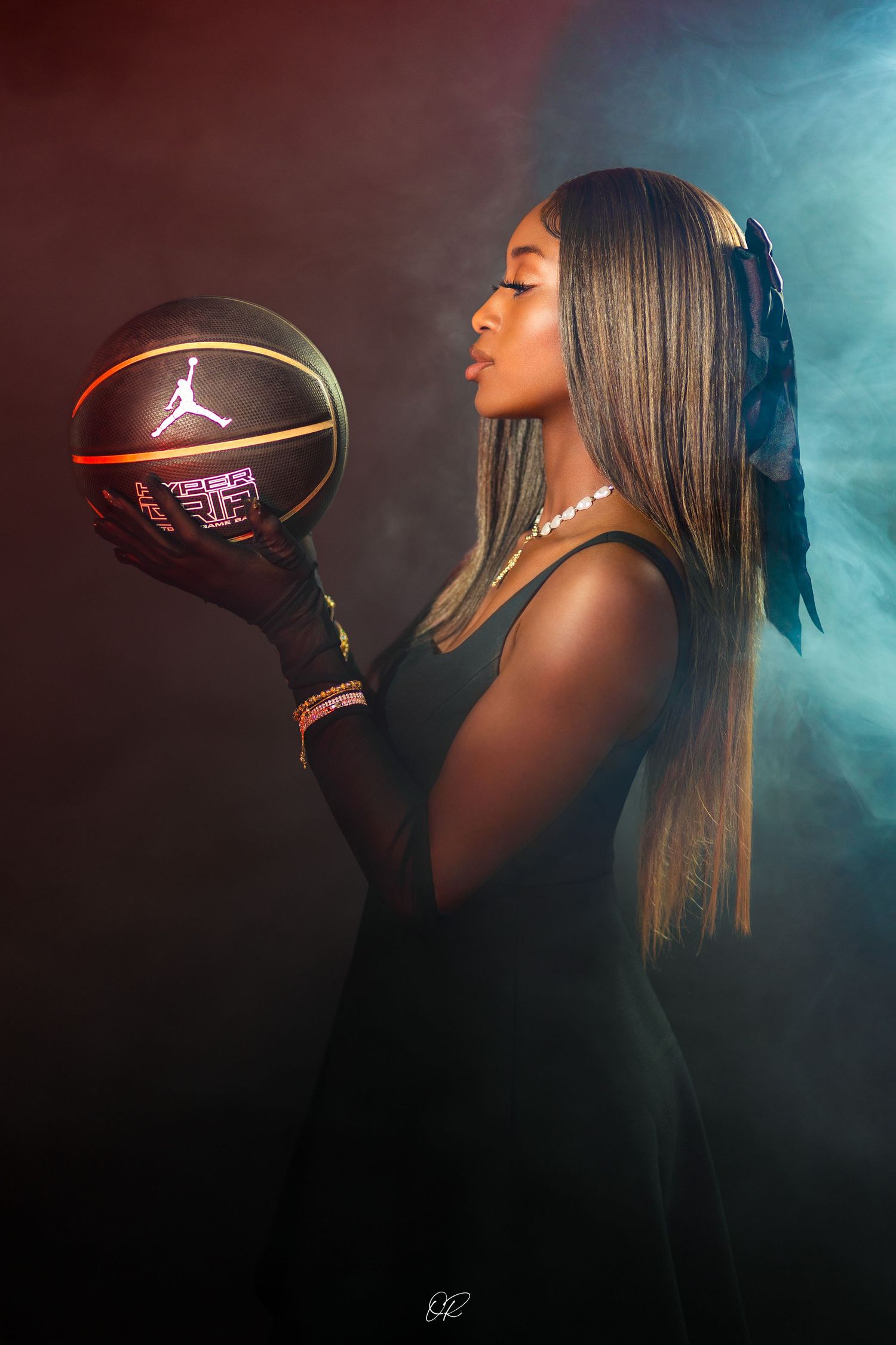 Basketball player poses with illuminated Jordan basketball in dramatic studio lighting with smoke effects.