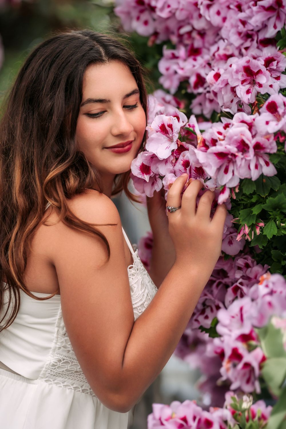 A person in white lace stands among blooming pink cherry blossoms, creating a romantic spring portrait.