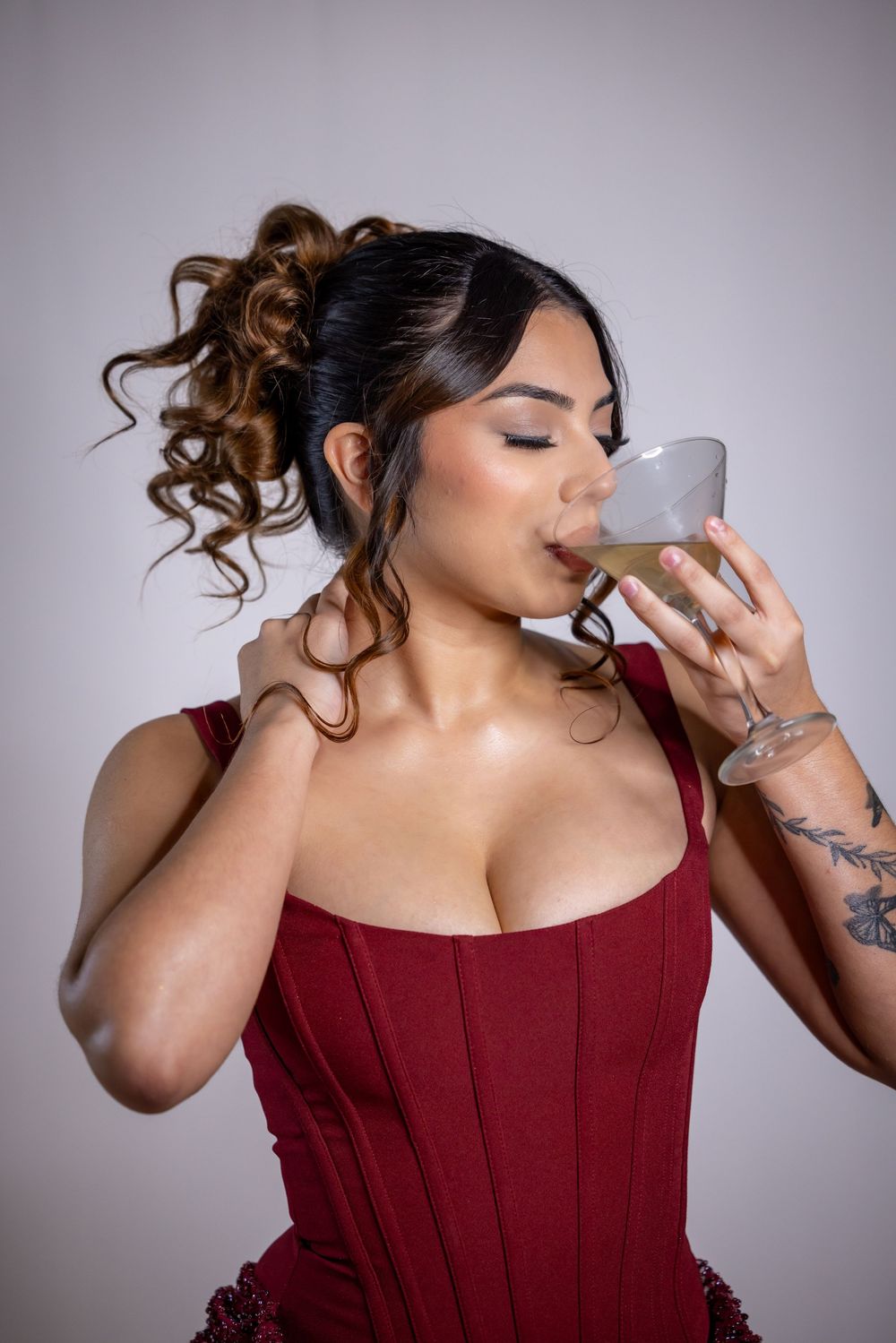 Person in burgundy dress takes sips from glass in artistic photo sequence showing progression of drinking motion.