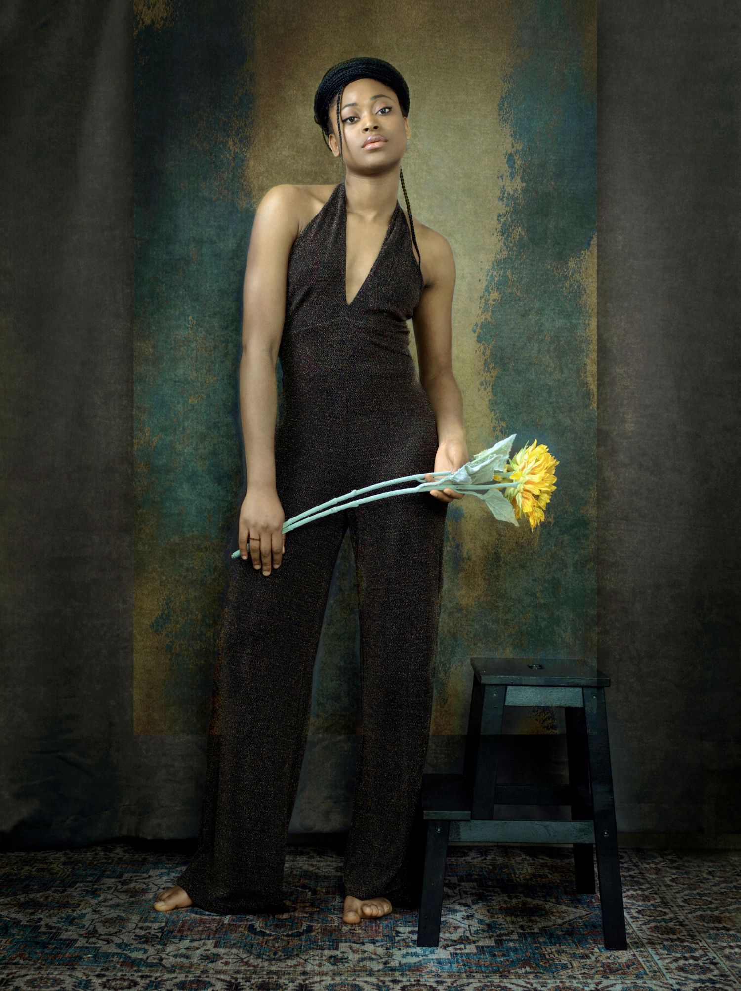 Artistic portrait series showing figure in black outfit against textured wall with yellow daffodil flowers.