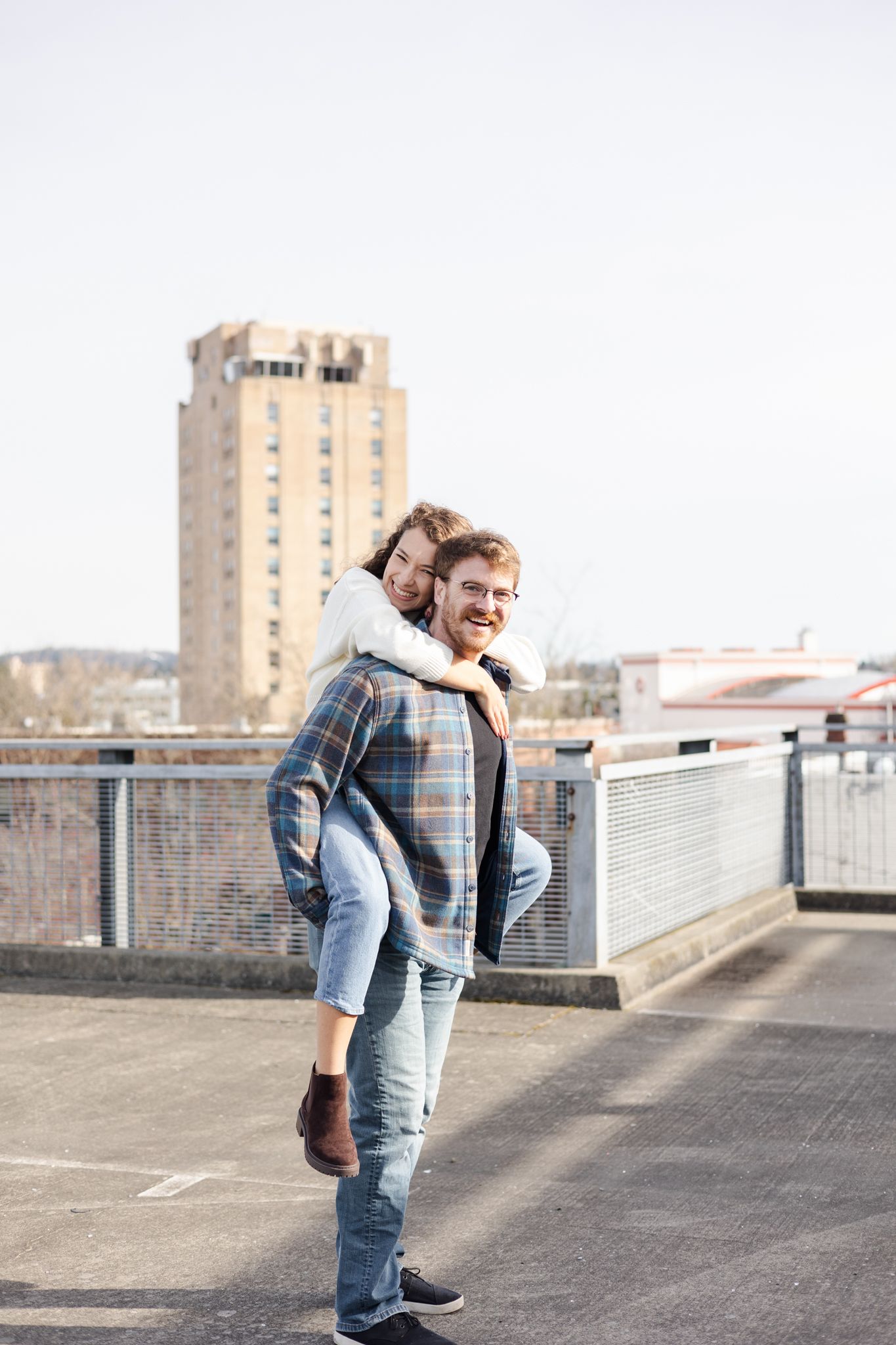 Person in casual wear posing on an urban rooftop with a tall building in the background.