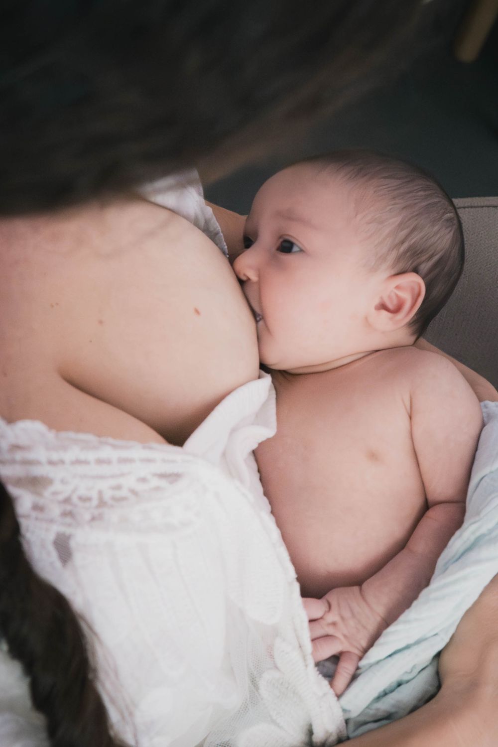 Baby nestled into mama’s chest during a peaceful breastfeeding moment at golden hour.