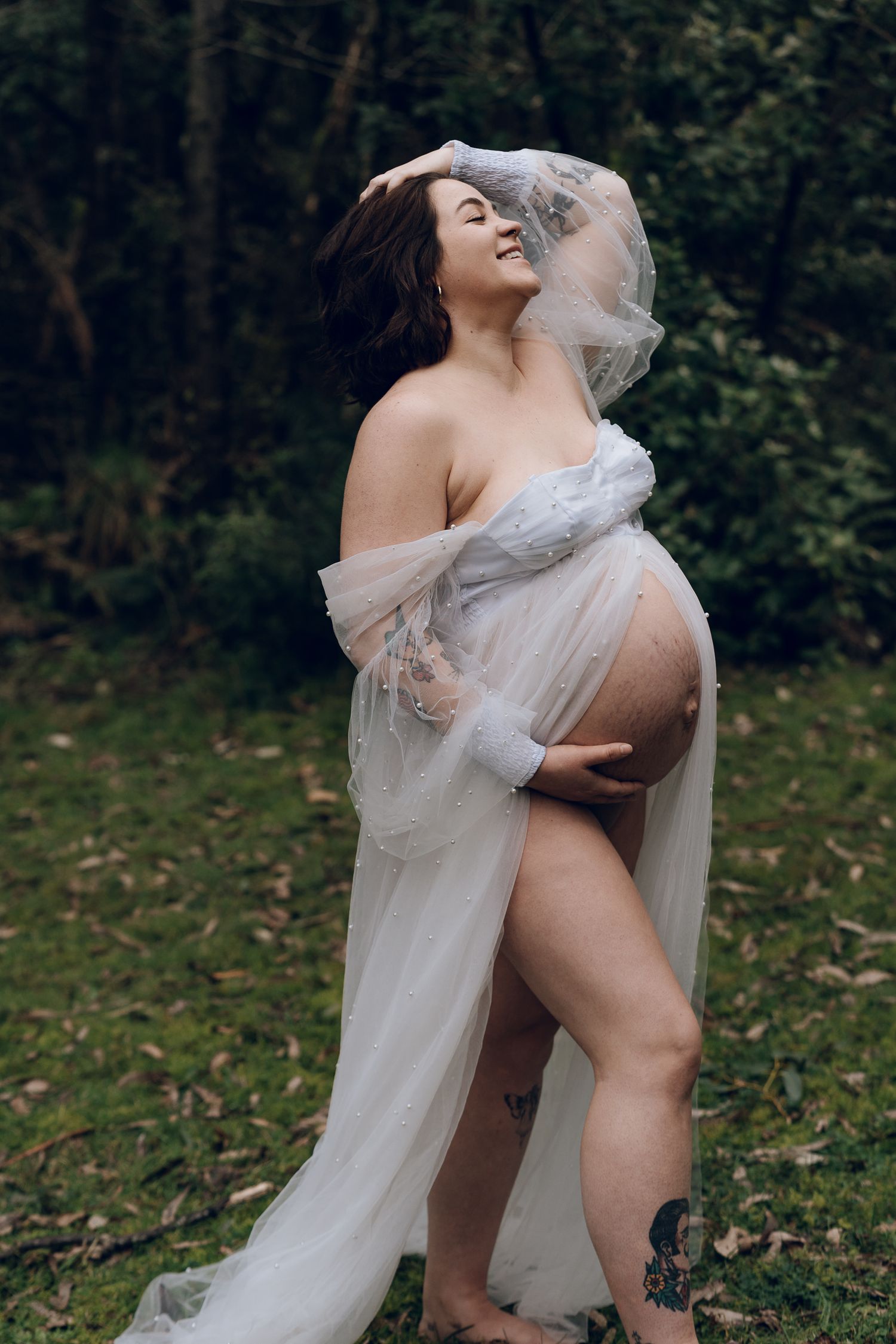 Romantic couple in wedding attire embracing in woodland setting.