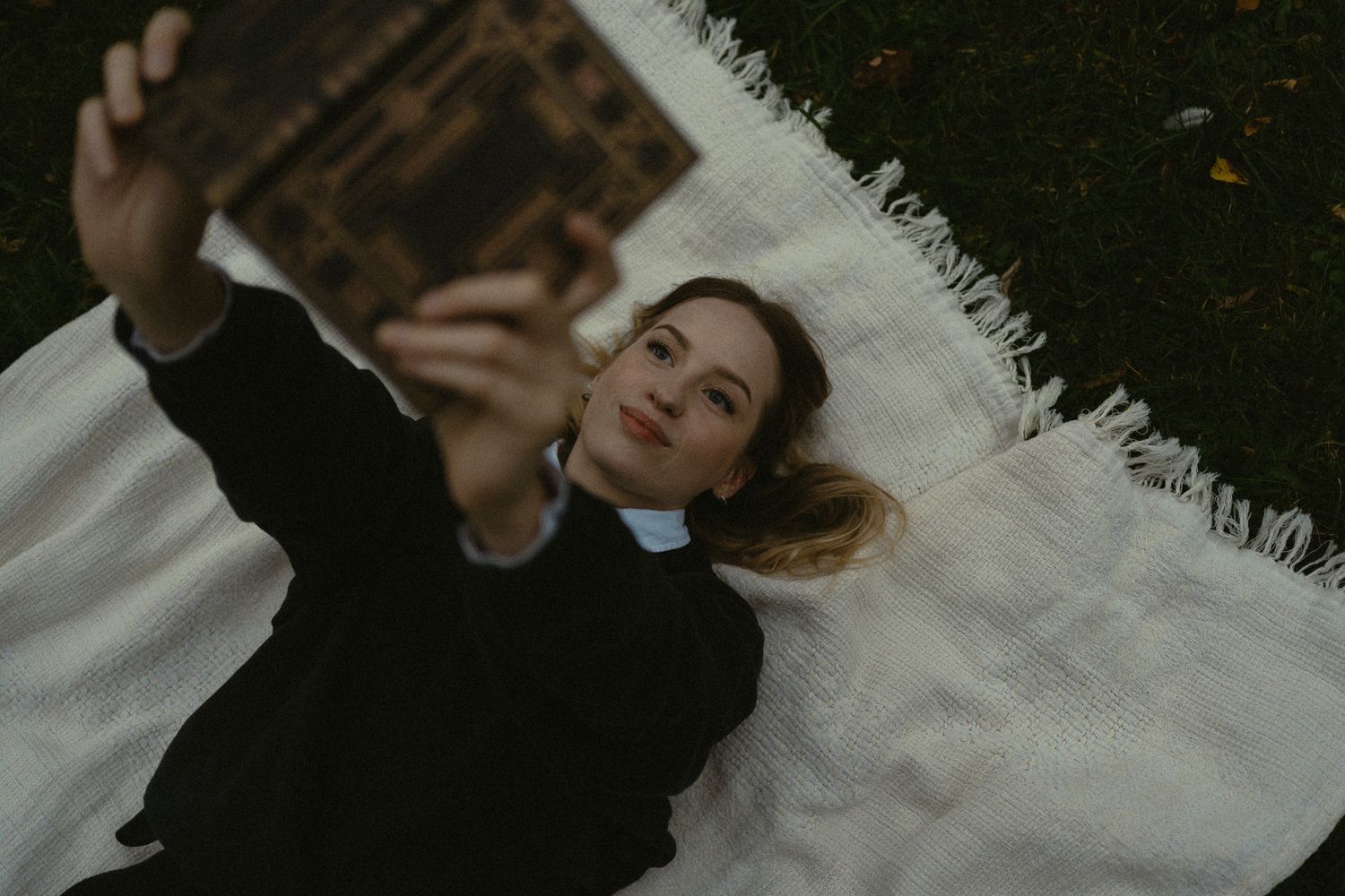 Romantisches Portrait Fotoshooting im Großen Garten in Dresden - Frau liegt mit dem Rücken auf  weißer Decke und liest ein Buch