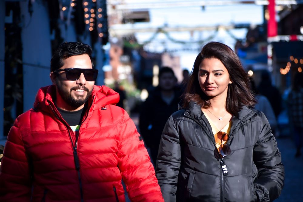 Couple in winter jackets walking together at a festive outdoor market. Toronto GTA