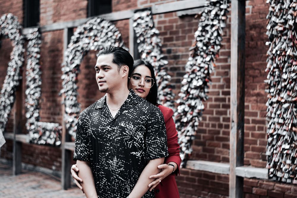 Stylish couple posing together near a decorative brick wall backdrop. Toronto GTA