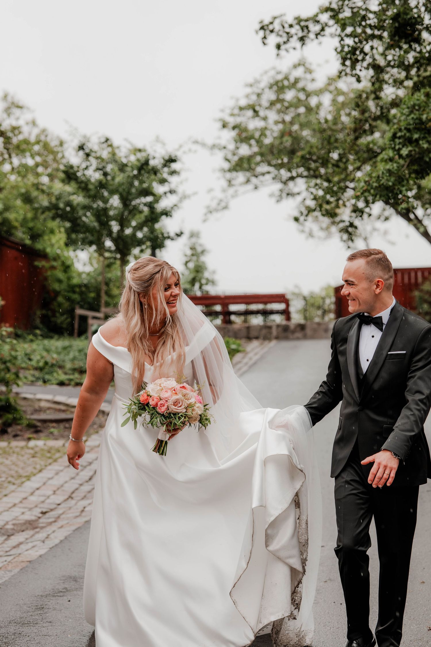 Brudpar går i regn och håller upp klänningen
