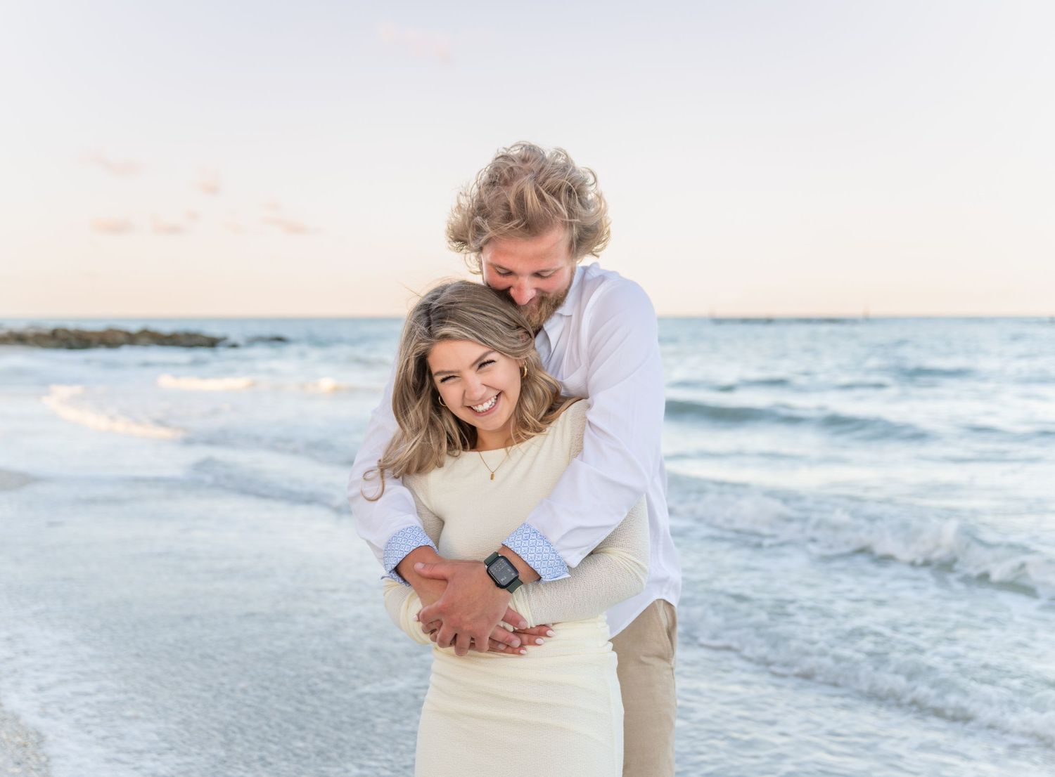 Family portrait on rocky beach overlook with ocean waves in background.