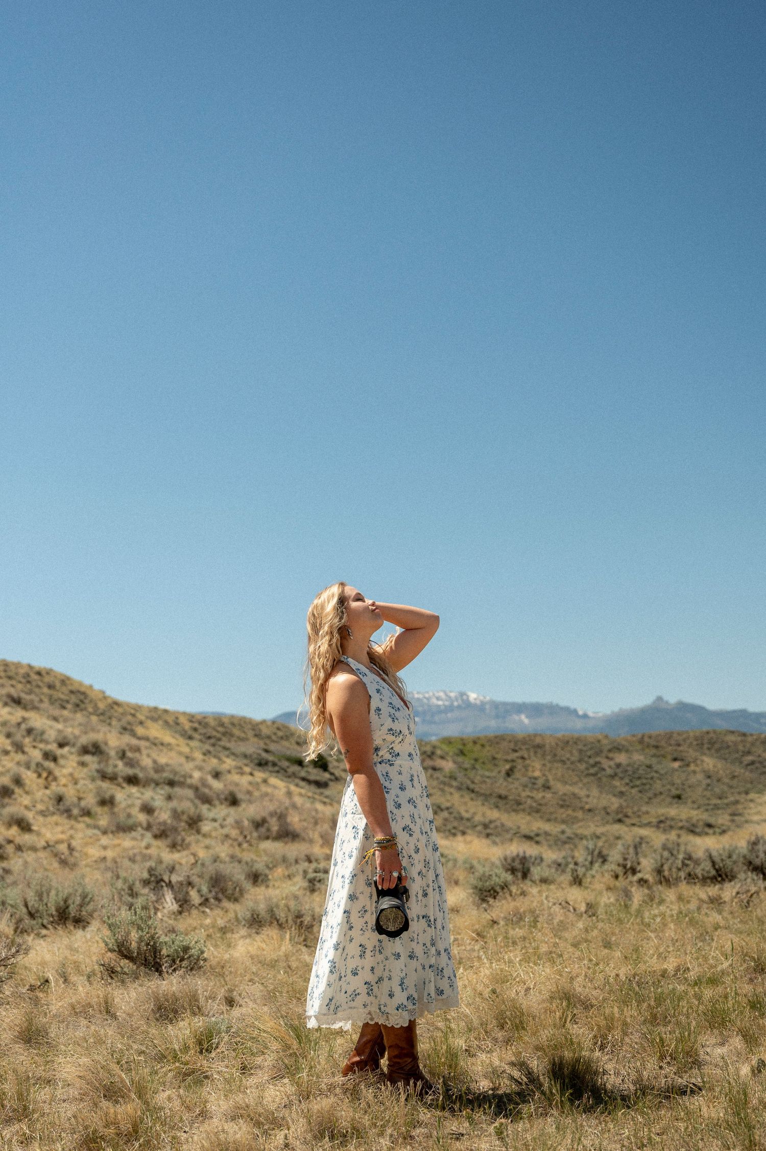A photographer with long hair bends down to capture a shot with a professional camera.