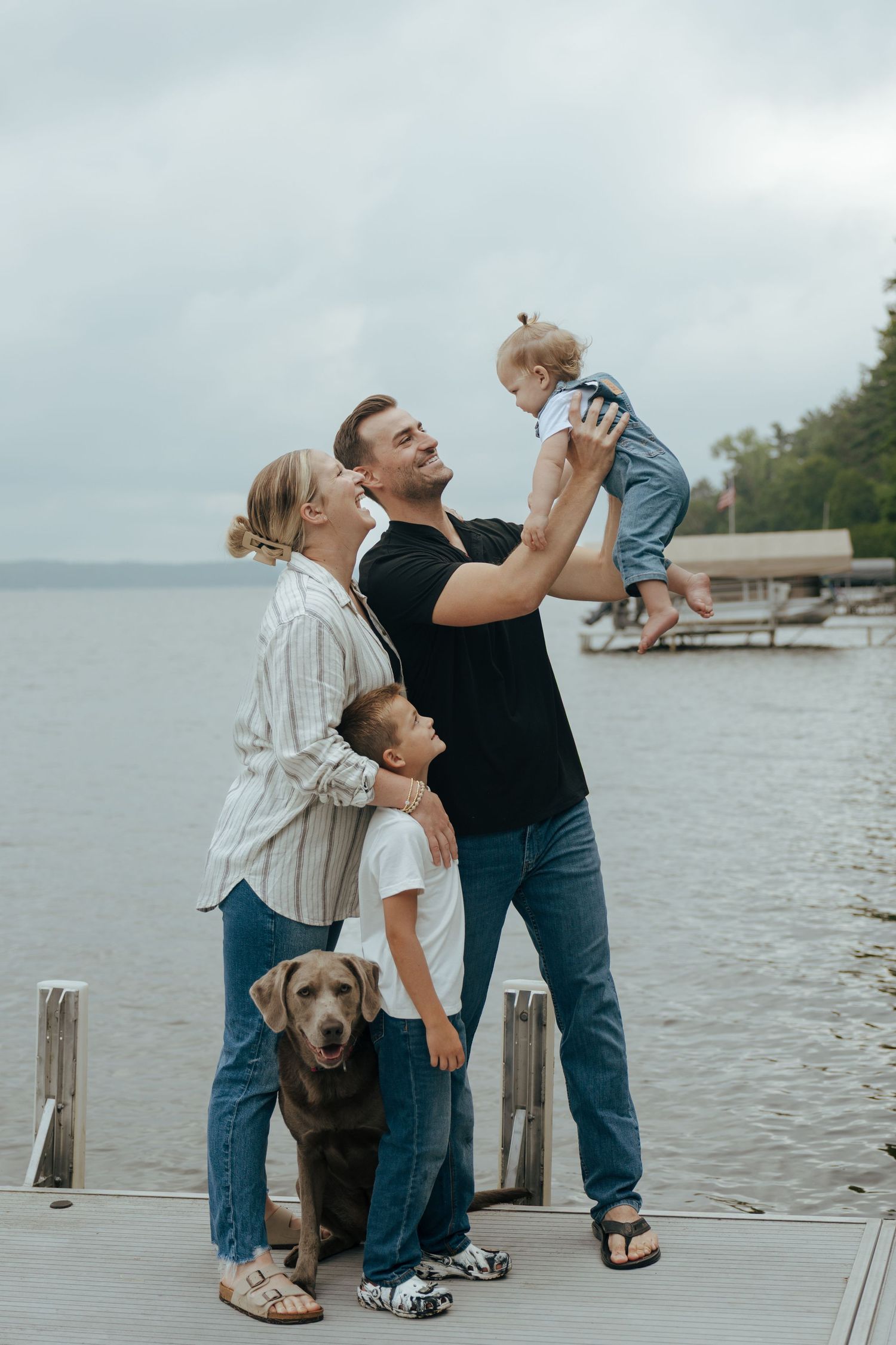 Family enjoying playful moment together on wooden dock by the water.