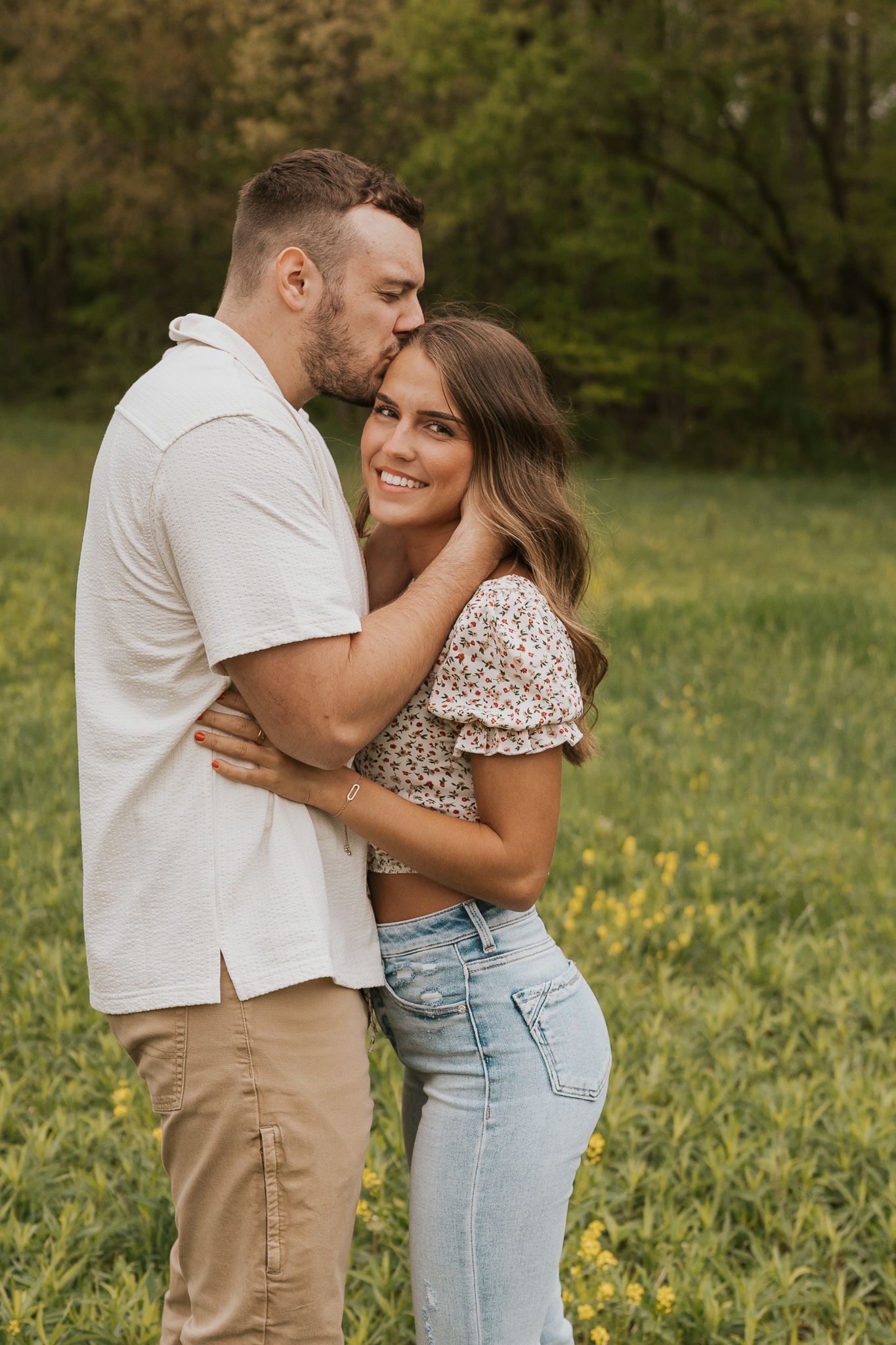 Engagement photograph showing intimate moments in a sunny meadow wearing casual outfits.