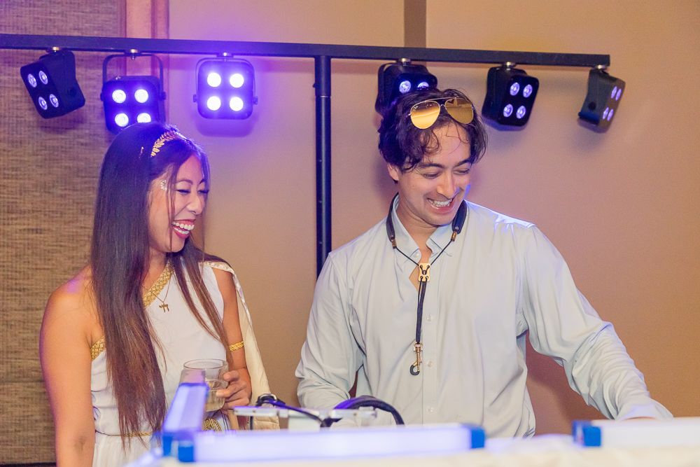 People seated at a table with purple lighting and decorative elements in the background.