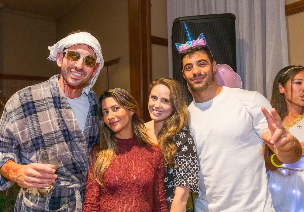 A group of friends pose together at a festive party wearing casual attire and party accessories.