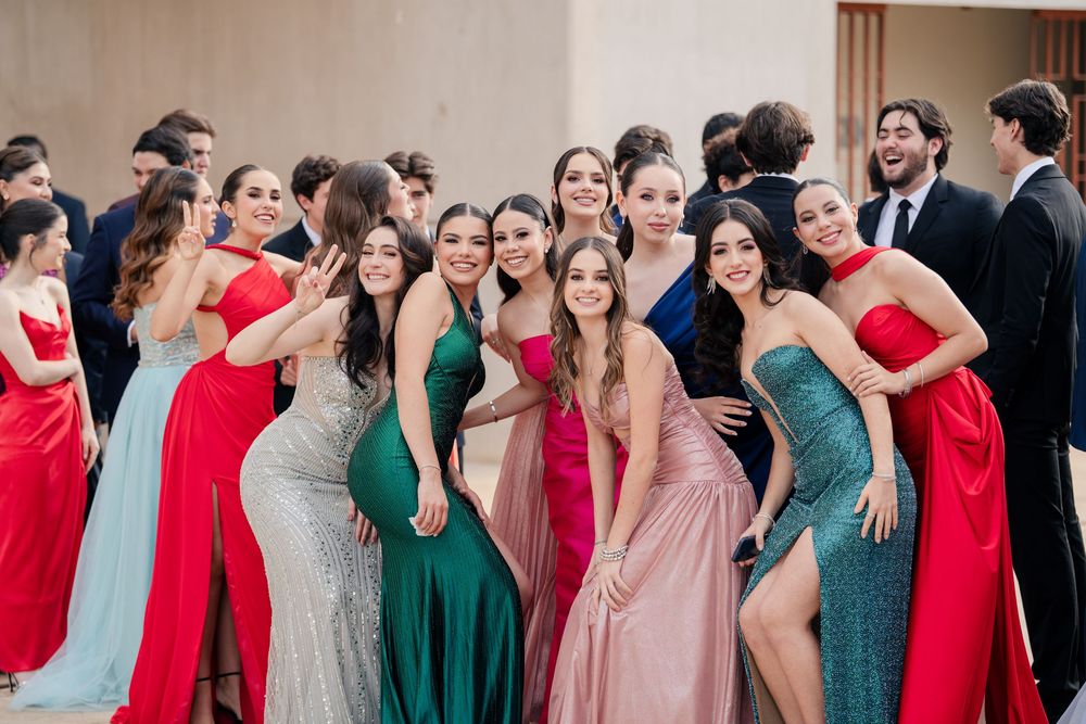 Large wedding party group photo featuring bridesmaids in colorful dresses ranging from red to green.