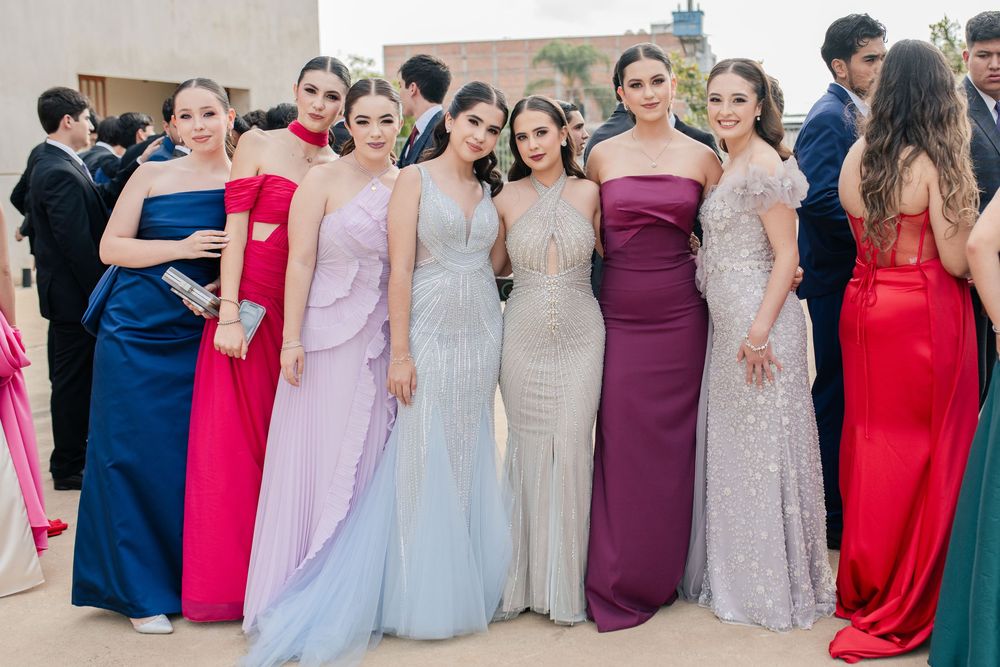 Formal group photo of wedding party members wearing elegant gowns in various colors and styles.
