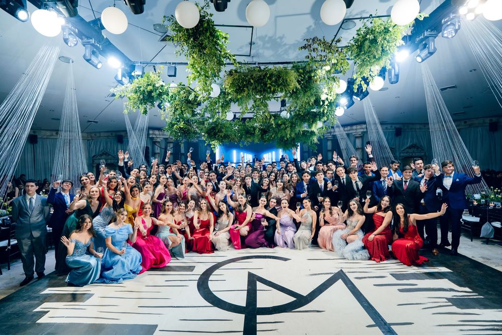 Wide angle shot of a formal event space with dramatic lighting and a large crowd seated in rows.