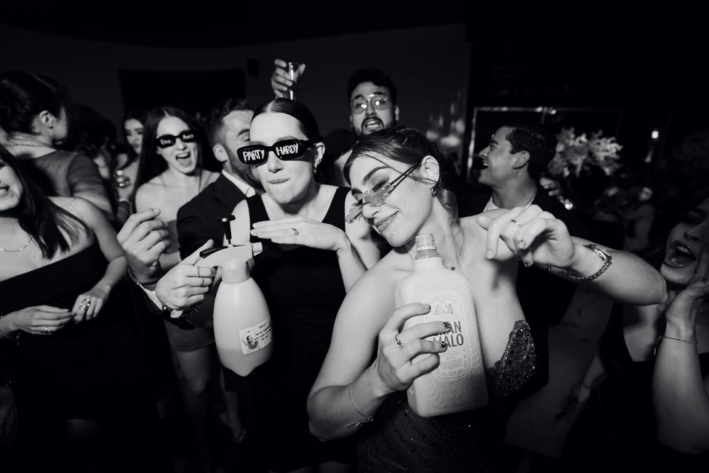 Black and white panoramic shot of party guests celebrating at a nighttime event.