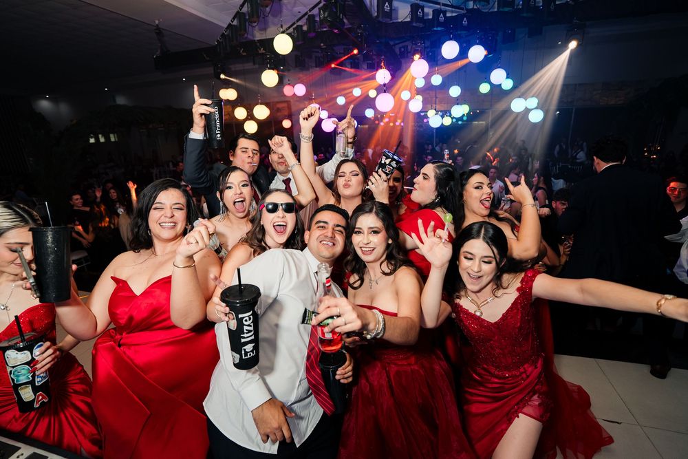 Energetic party crowd dancing and celebrating under colorful venue lighting.