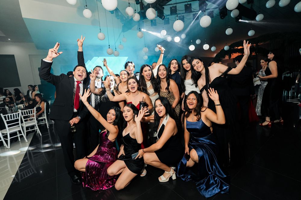Celebratory party scene with dancing crowd under glowing lights and decorations.