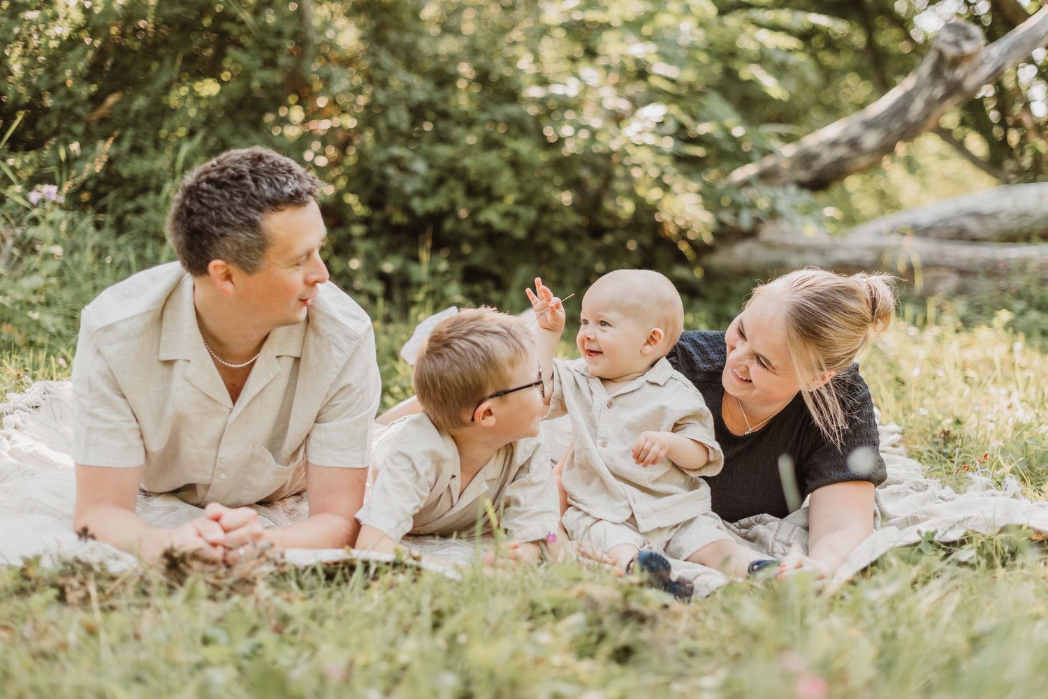 A playful family moment lying in grass with coastal views in the background.