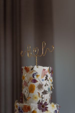 Close up crop of the top of a wedding cake. natural flowers stuck to the sides. rustic, wild flower, beautiful wedding