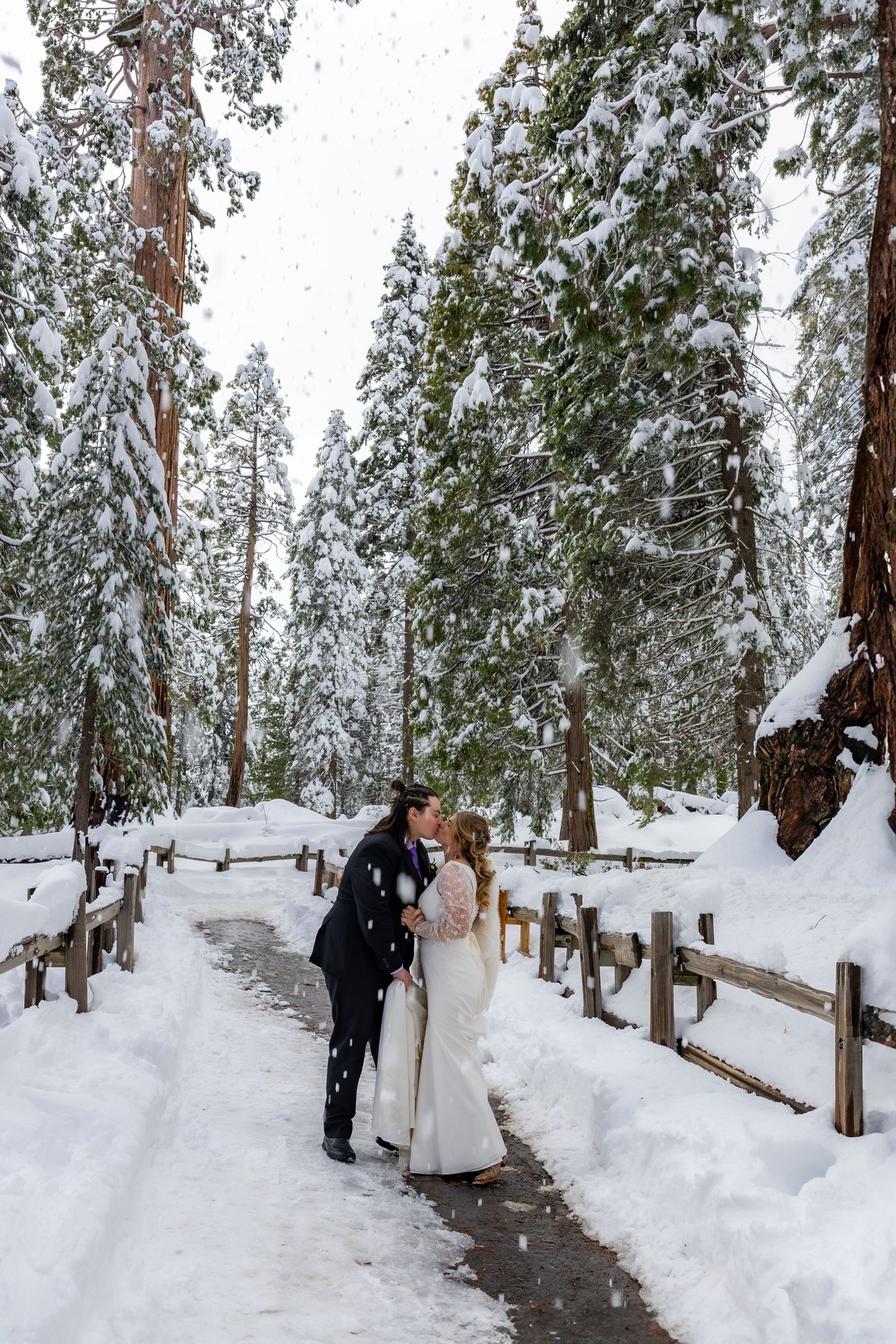 An expectant couple shares an intimate moment outdoors, with mother wearing a vibrant red dress.