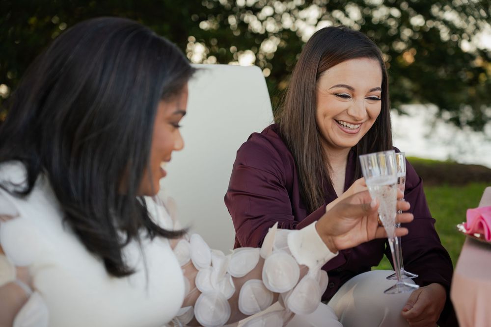 Two people laughing and enjoying coffee together outdoors on a sunny afternoon.