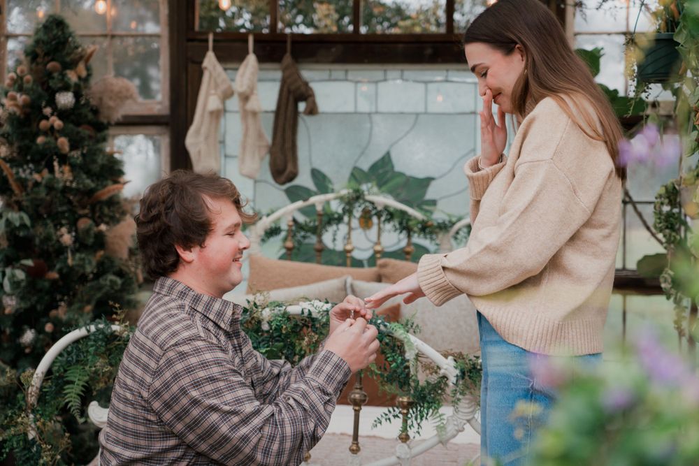 Romantic outdoor proposal scene with decorative lighting and greenery.