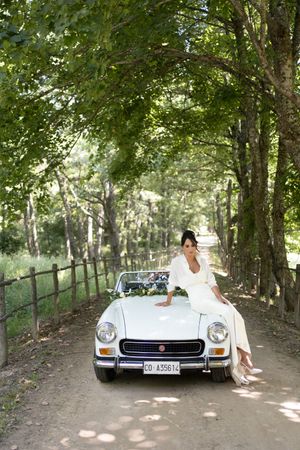 Vintage white Mercedes parked under tree canopy for wedding photos.