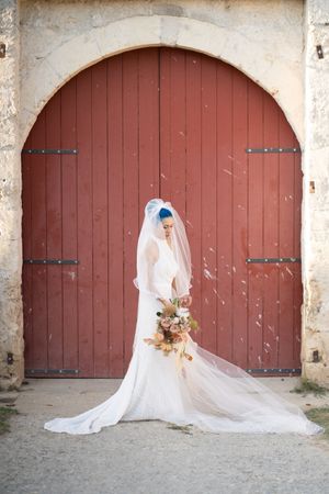 Bridal portraits against rustic red barn doors with flowing cathedral veil.