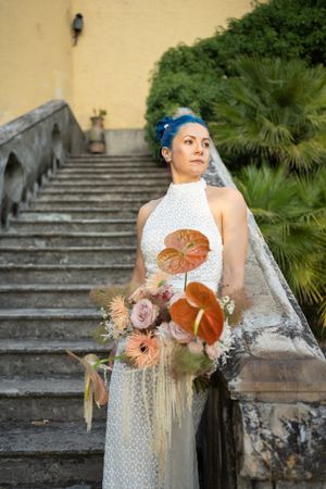 Bridal portrait on stone steps with peach and coral bouquet.