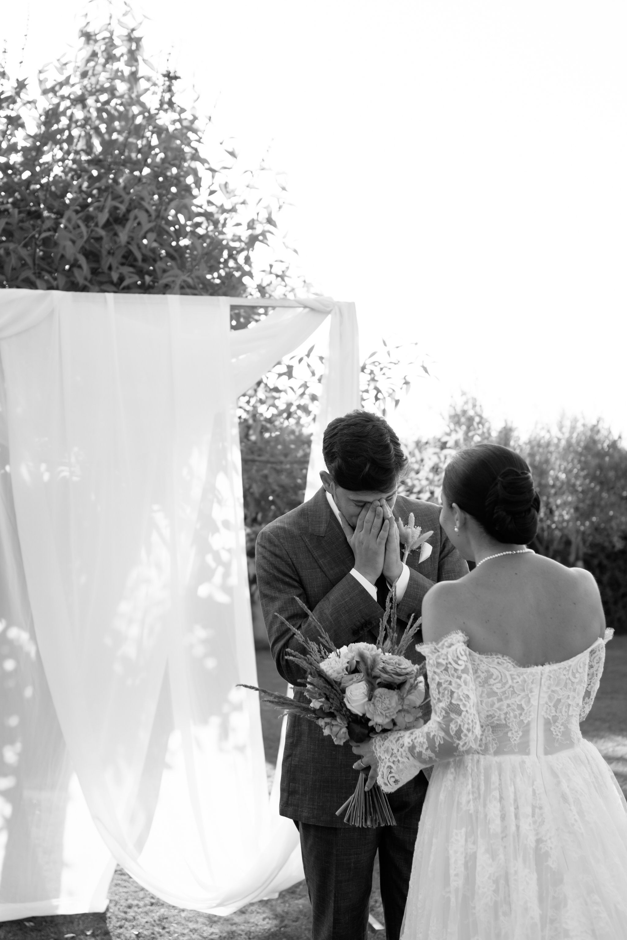 Black and white wedding photo of couple walking together outdoors.