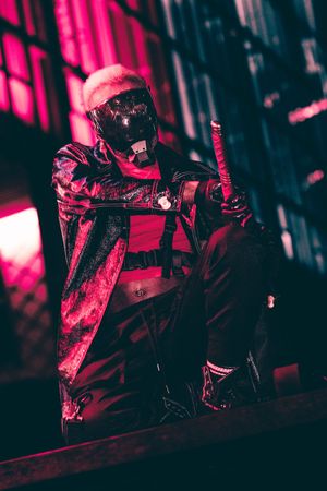 Metal performer on dark stage bathed in intense pink and red lighting creating dramatic atmospheric effect.