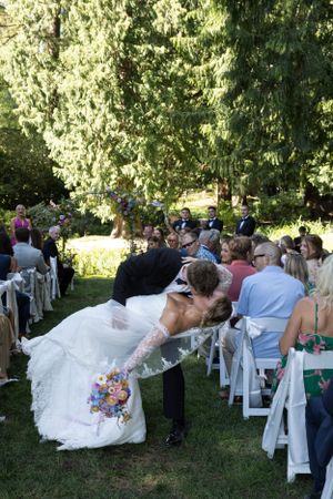 Cora Emilie Media A wedding couple shares a romantic dip kiss during their outdoor garden reception.