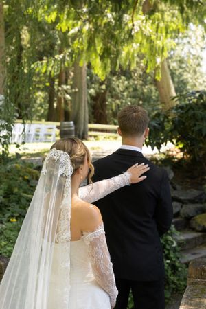 Cora Emilie Media Bride and groom share romantic moments in a lush garden setting with flowing veil details.
