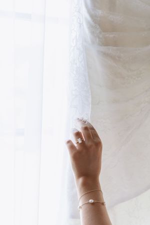 Cora Emilie Media Close-up shot of a bride's hand with jewelry against white tulle fabric.