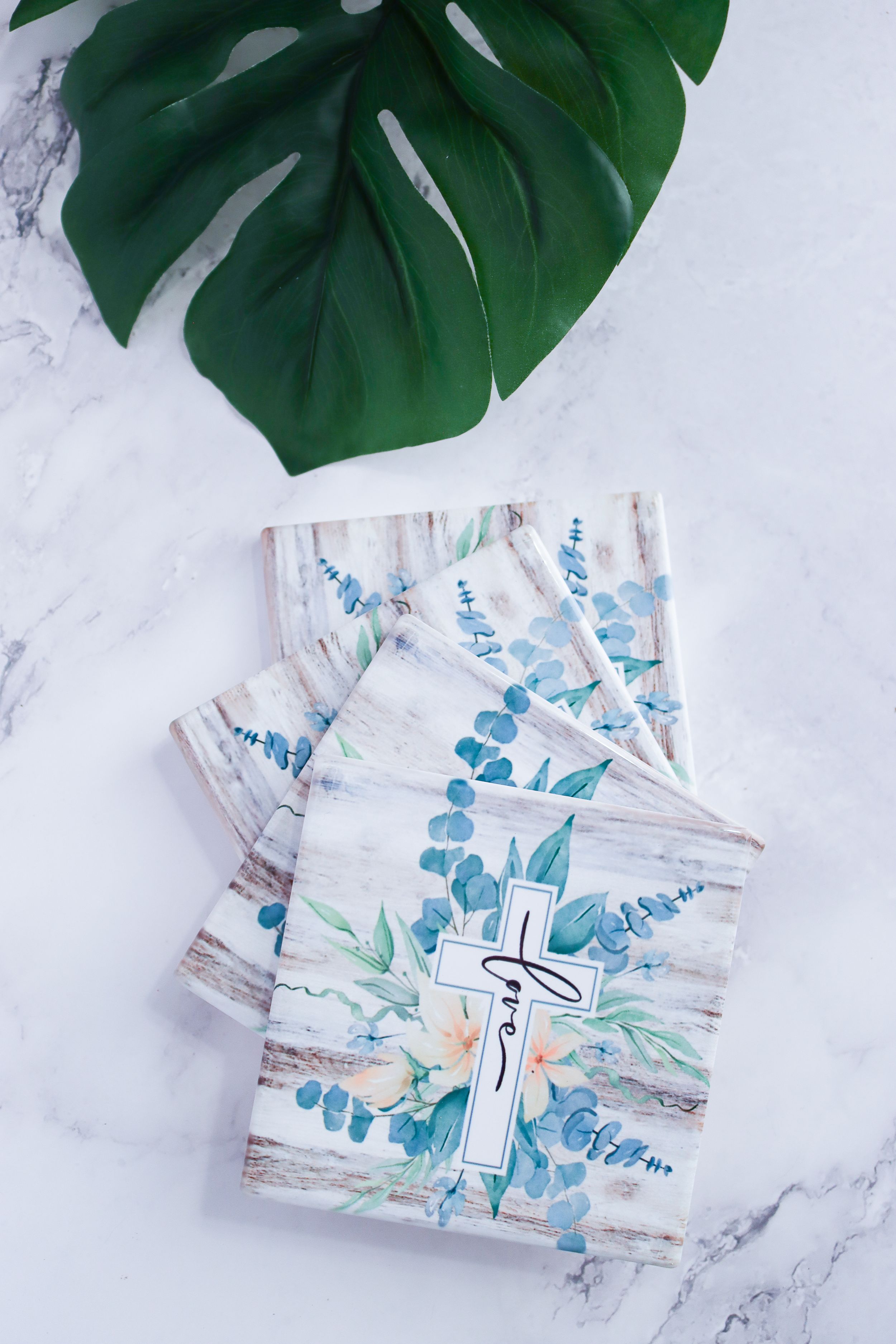 Watercolor business cards with blue and green botanical designs on white marble surface.