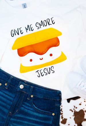 White t-shirts with playful designs paired with blue jeans on textured background.