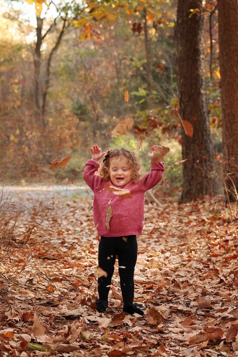 candid photo of toddler playing in the leaves in the autumn in Lakewood, NJ