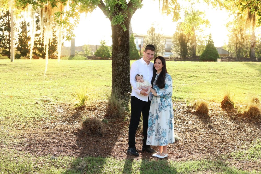 a sun drenched image of a mother and father cradling their infant girl