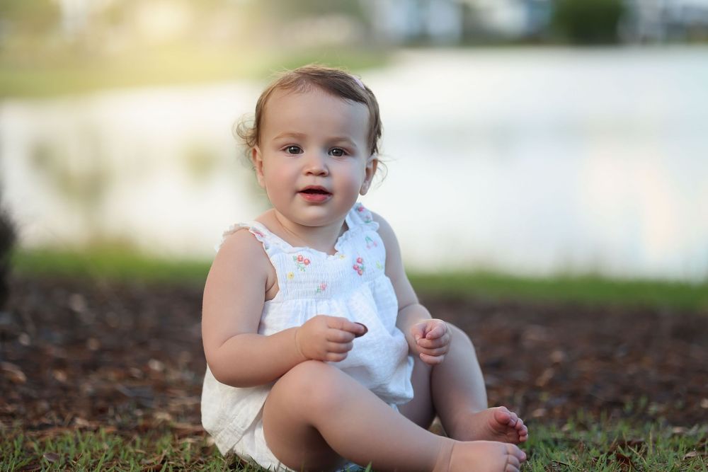 adorable toddler girl wearing a white outfit with a beautiful lake in the background