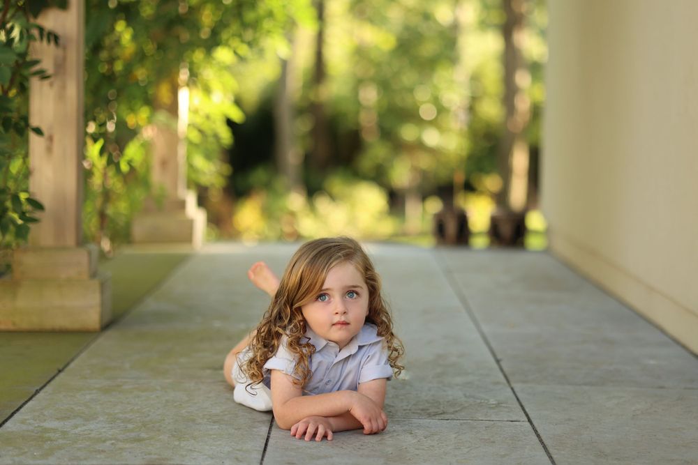 Child posing on outdoor walkway in Jackson, NJ surrounded by greenery, showcasing natural light photography